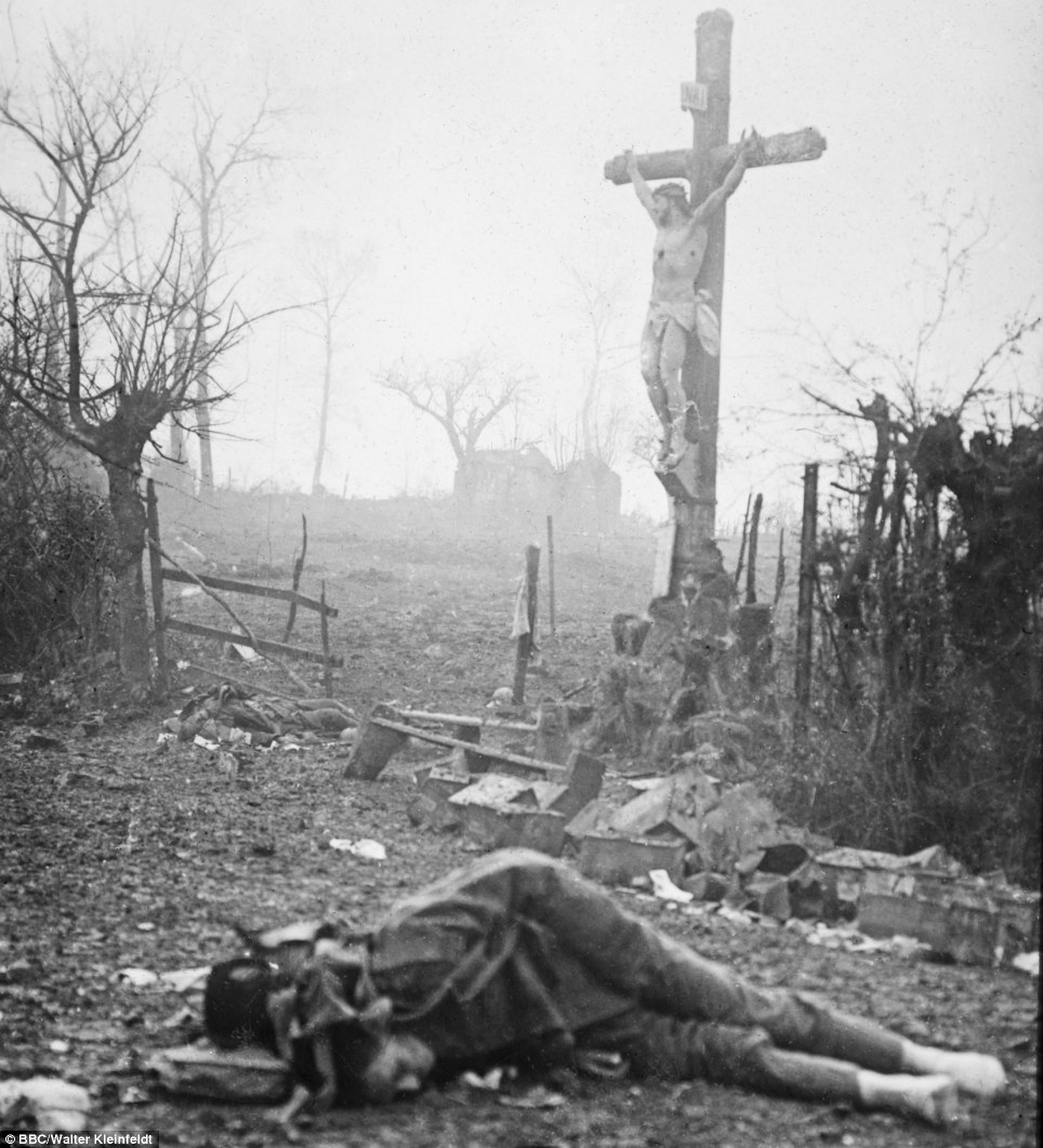 Carnage: Amid the appalling devastation and bodies of dead soldiers, a crucifix stands tall - miraculously preserved from the shell fire. The powerful image was captured after a bloody skirmish in 1917 - and Walter's son Volkmar says: 'This photograph is like an accusation - an accusation against war'
